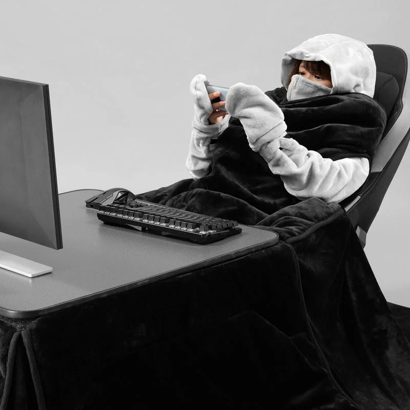 フード付きブランケットを着用した人物がスマホ操作