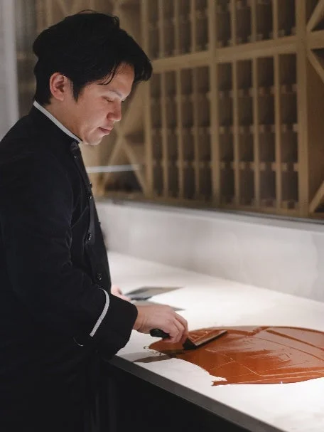 黒いコック服を着た男性が、菓子作りに取り組む川口純史氏