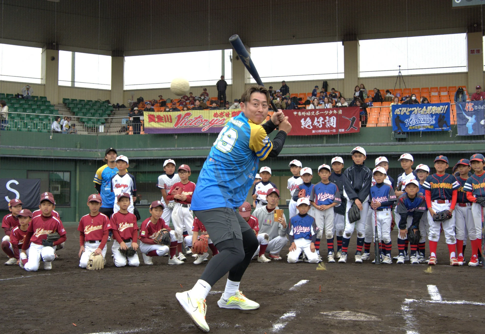 野球場で少年野球選手が指導を見る様子