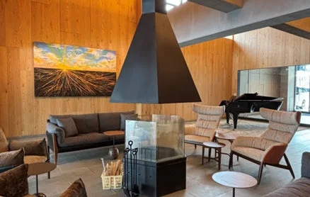 木製の壁が特徴的なモダンで広々としたラウンジ、暖炉とグランドピアノ