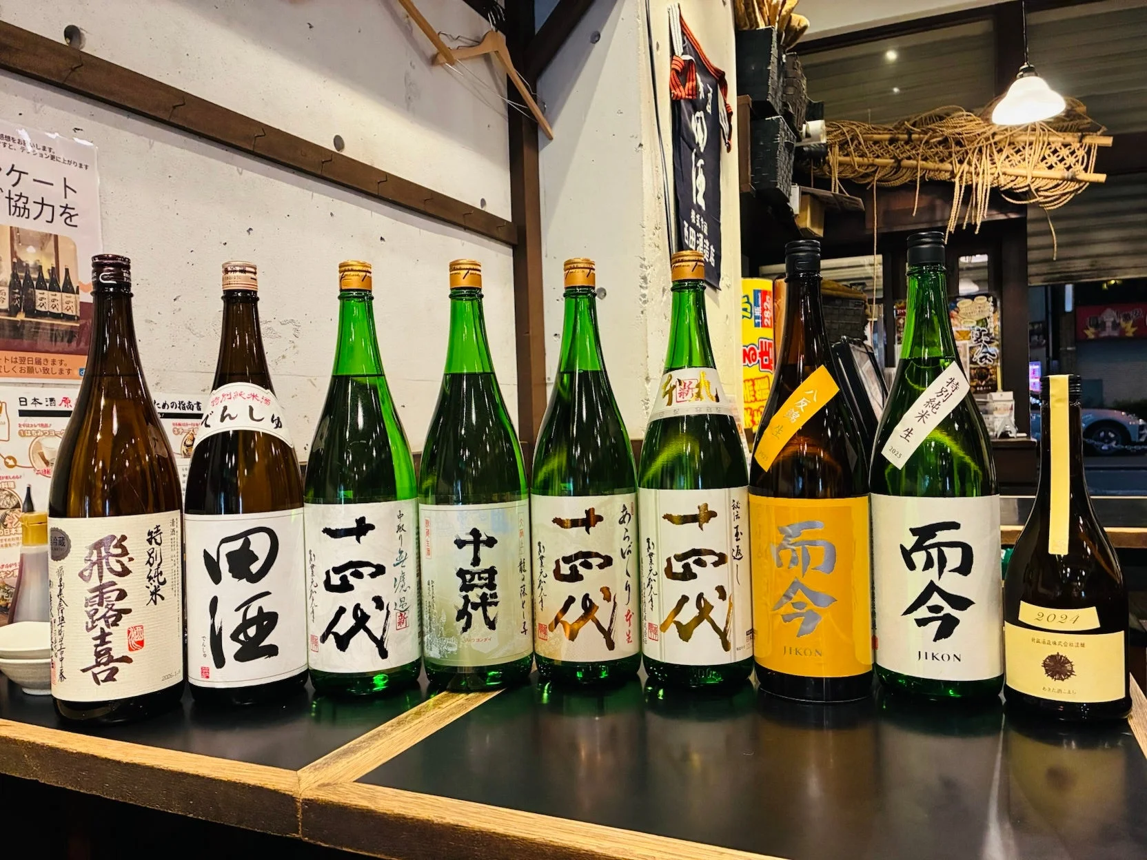 居酒屋のような店内で、日本酒の有名銘柄がずらりとカウンターに並べられています