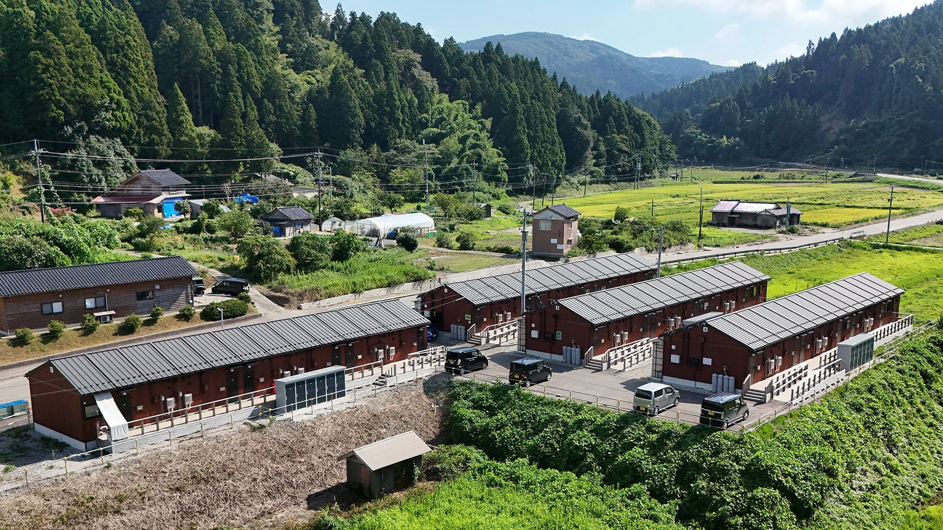 山間部の豊かな自然に囲まれた地域に、複数の低層の建物が並んでいます。