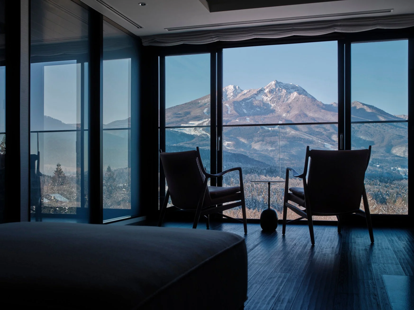窓から雪をまとった雄大な山々を望む、モダンで洗練された室内の様子