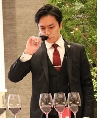ワイングラスを鼻に近づけ、真剣な表情でワインのテイスティングをしている吉田雄太氏