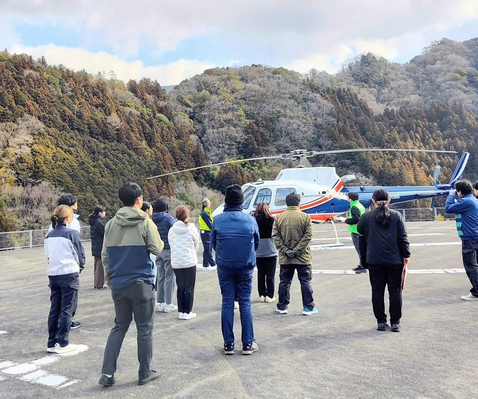 山を背景にしたヘリポートと人々