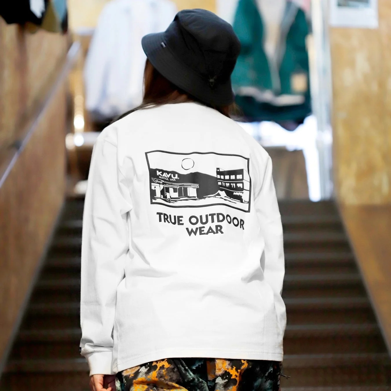 白い長袖Tシャツと黒いバケットハットを着用した人物の背面