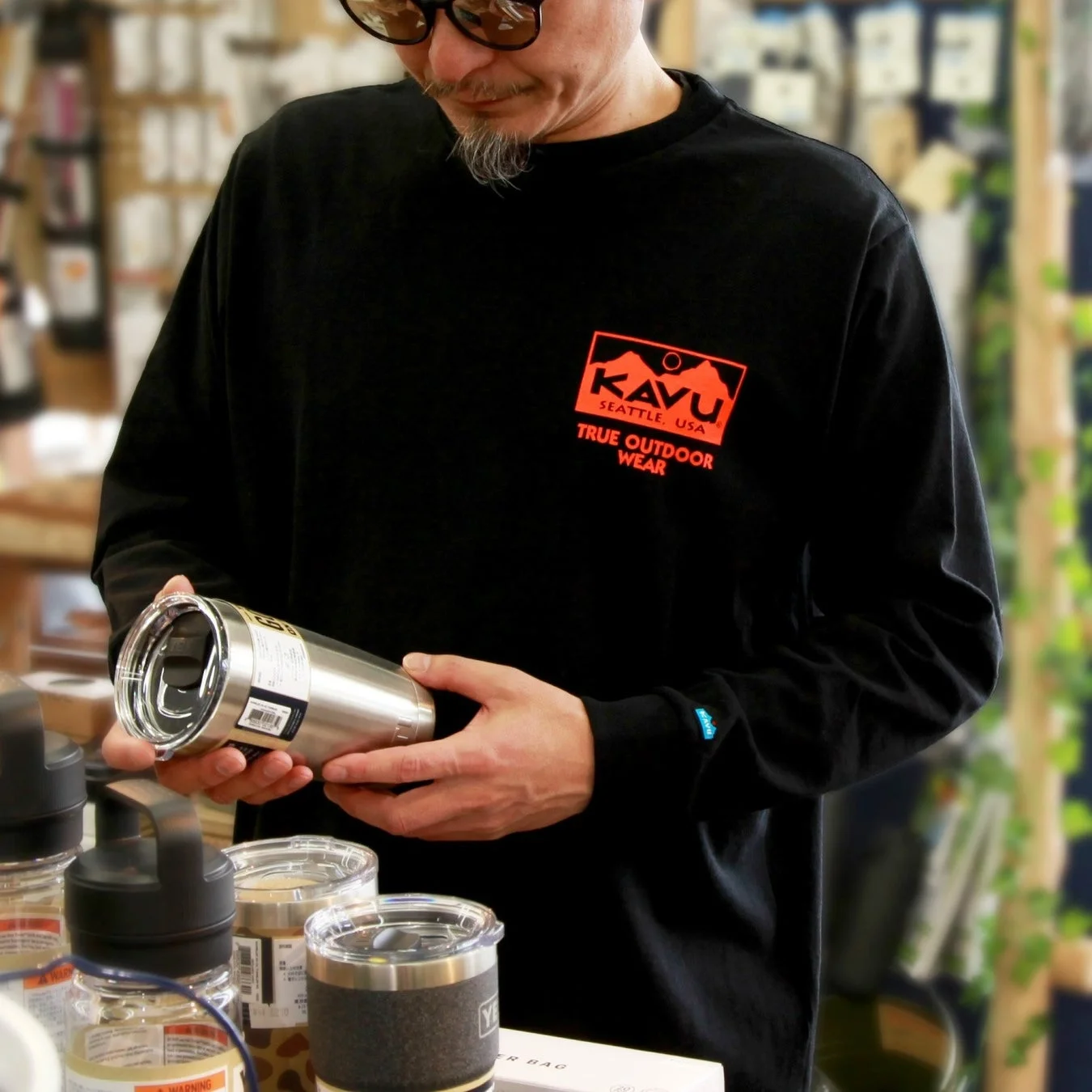黒いKAVUの長袖Tシャツを着た男性
