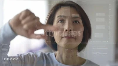 中年アジア人女性が、ホログラフィックなデジタルインターフェースを指で操作している様子