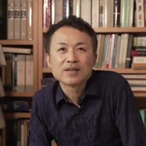 本棚の前で話す阿部公彦氏