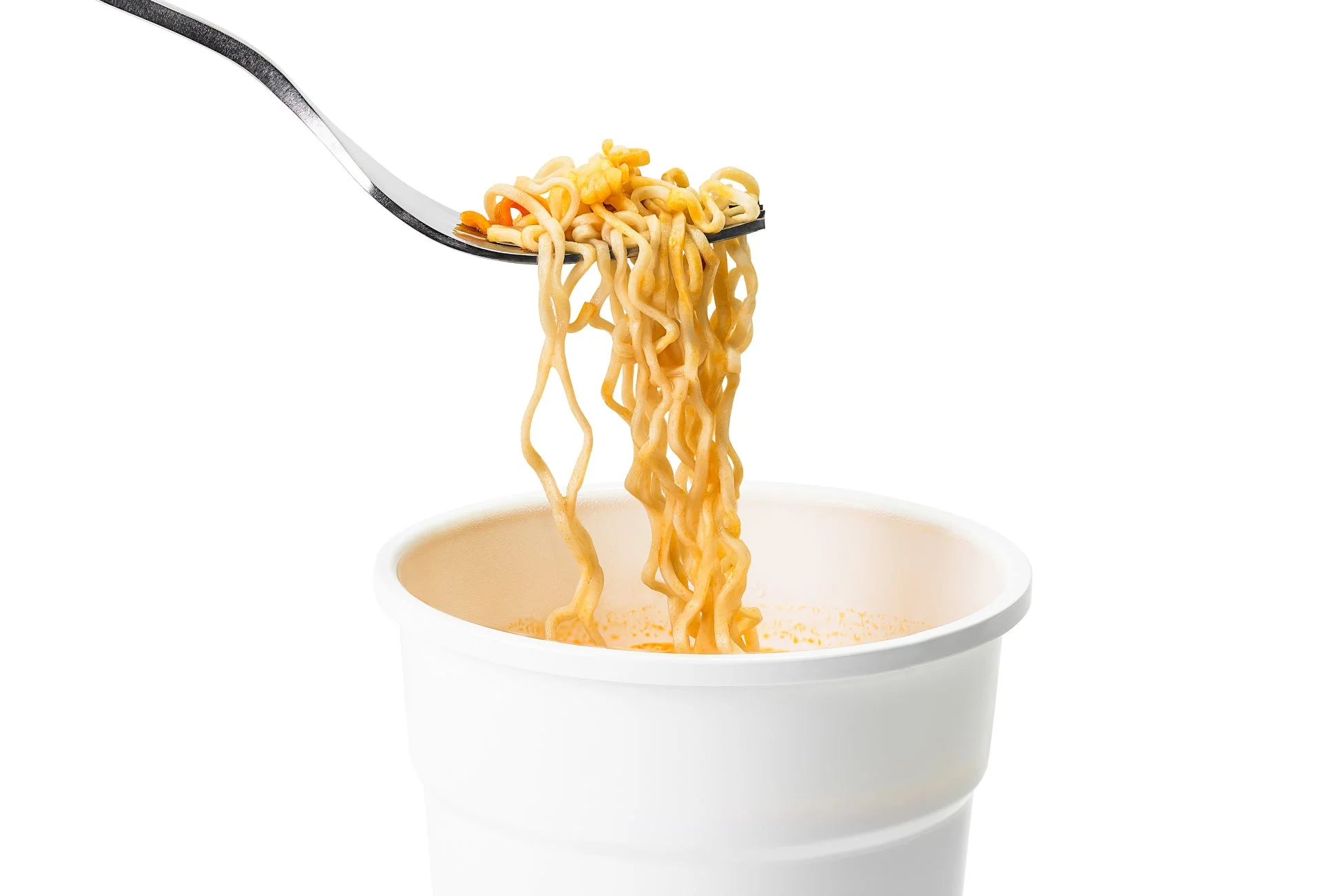 白い背景の前で、フォークが白いカップ麺から麺を持ち上げている